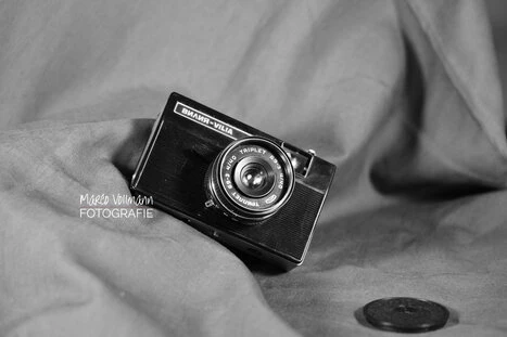 eine analoge Kleinbildkamera liegt schräg auf einem grauen Tuch